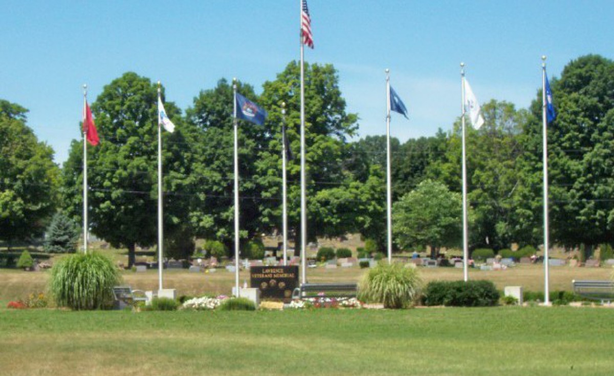 Flags and memorial at a Lawrence Township cemetery on a clear day.
